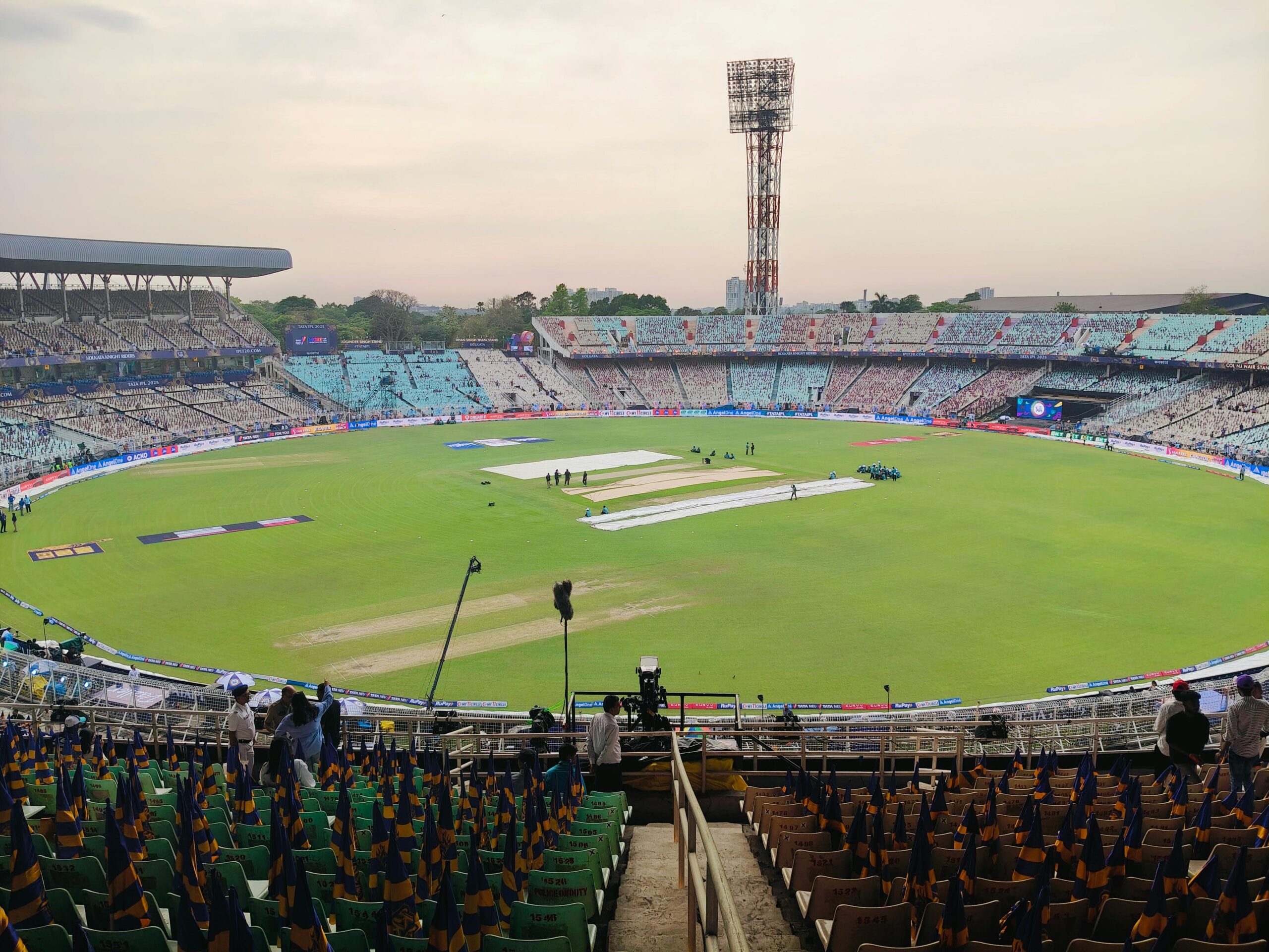 Wide-angle view of an iconic cricket stadium empty before a match, showcasing vibrant seating and green pitch.