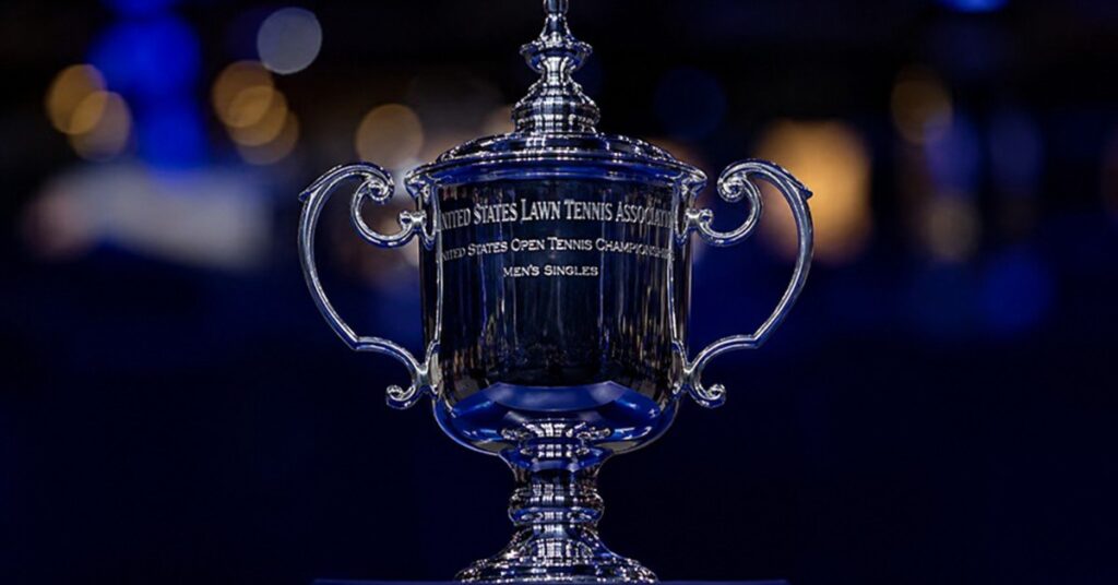 Silver US Open men’s singles trophy displayed against a dark blue tennis arena background, symbolizing the 2026 tournament.