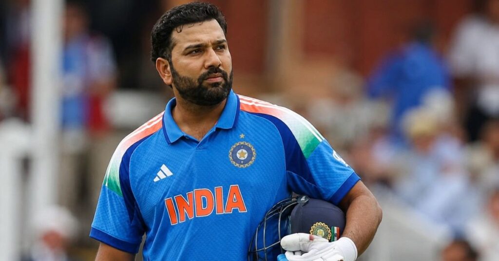 Rohit Sharma in India’s blue jersey holding his helmet and batting gloves on a cricket field.