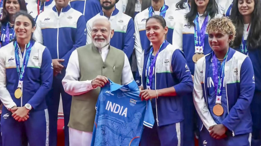 Harmanpreet Kaur presenting PM Modi with a jersey signed by the gold-winning squad. Harmanpreet Kaur presenting PM Modi with a jersey signed by the gold-winning squad.